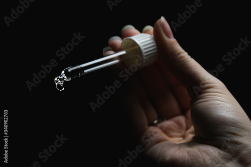 female with beautiful nails hold pipette isolated on black background