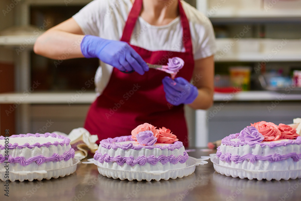 A pastry chef makes flowers from cream to decorate cakes.