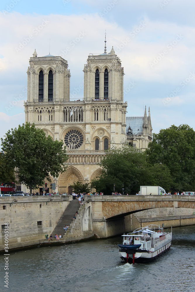 Fototapeta premium Paris, France - August 26, 2018: Tourists enjoy a boat trip on Seine river near Notre Dame cathedral.