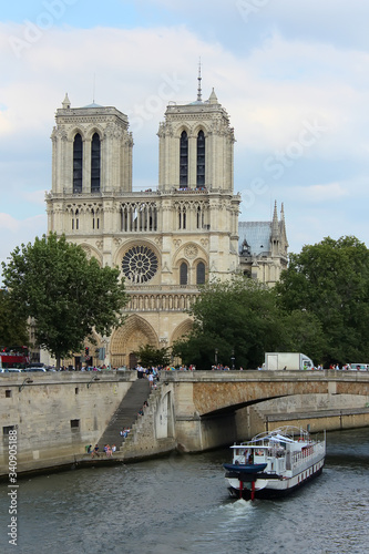 Paris, France - August 26, 2018: Tourists enjoy a boat trip on Seine river near Notre Dame cathedral.