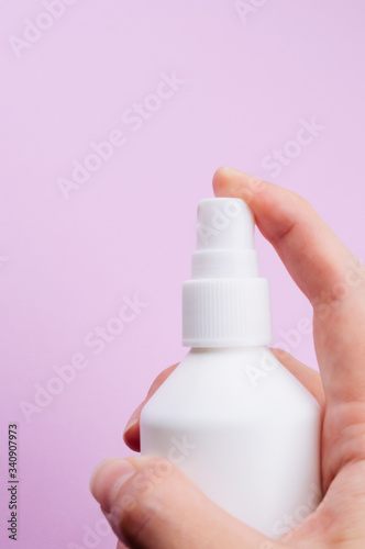 Hand sanitizer bottle isolated on purple background in womans hand. Corona protection. 