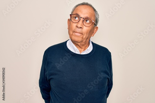 Senior handsome grey-haired man wearing sweater and glasses over isolated white background smiling looking to the side and staring away thinking.