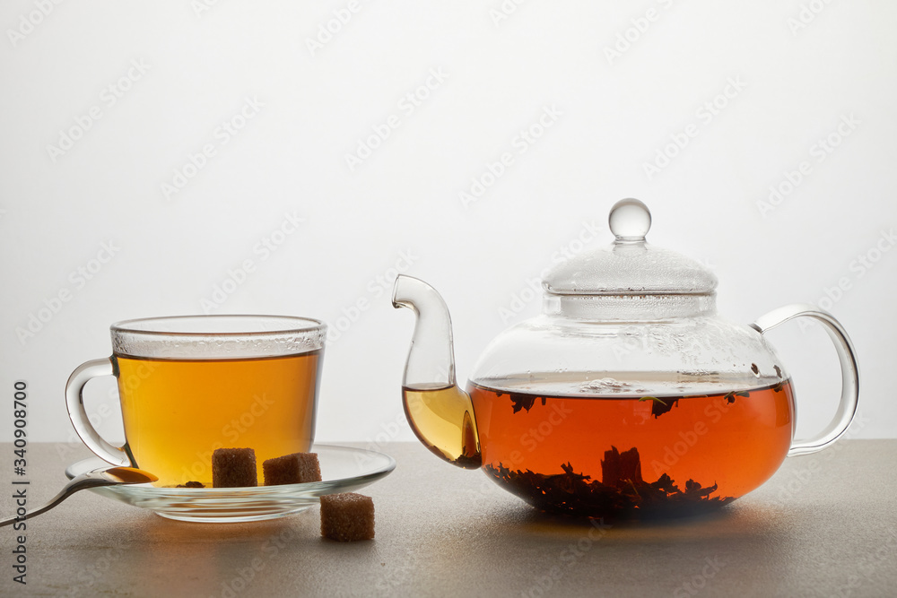 Cup and teapot of green tea with lemon and sugar isolated on white Cup and teapot of green tea with lemon and sugar isolated on white