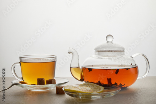 Cup and teapot of green tea with lemon and sugar isolated on white