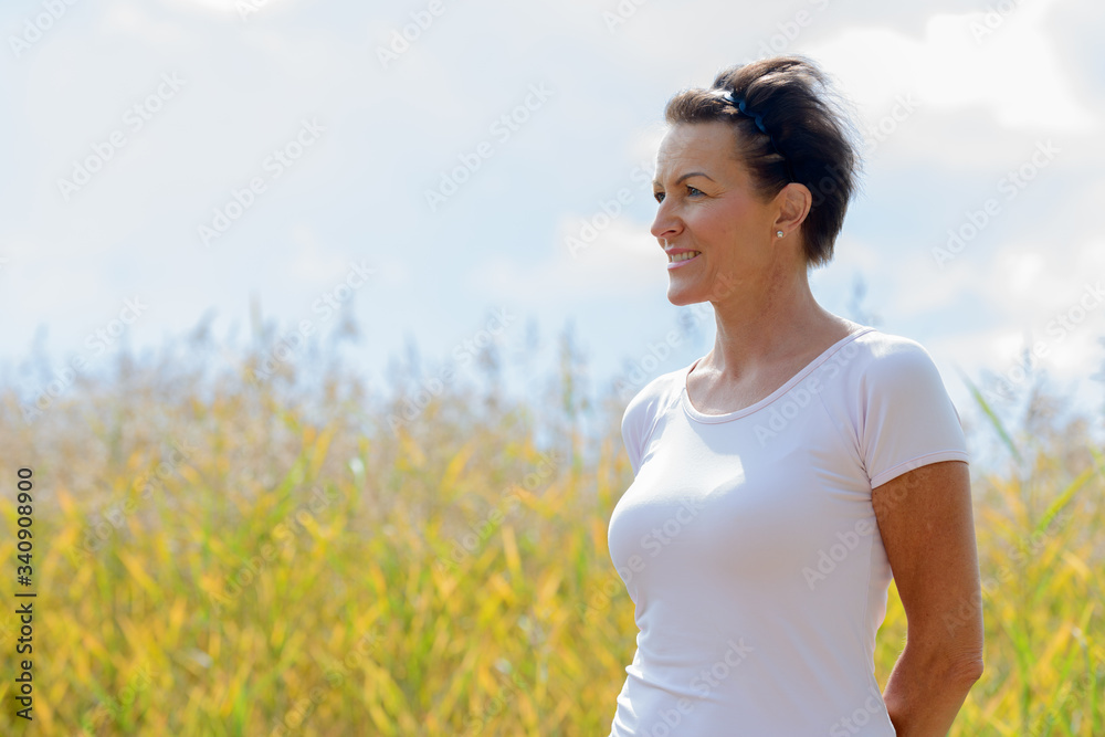 Mature beautiful woman relaxing in the fields of tall grass Mature beautiful woman relaxing in the fields of tall grass