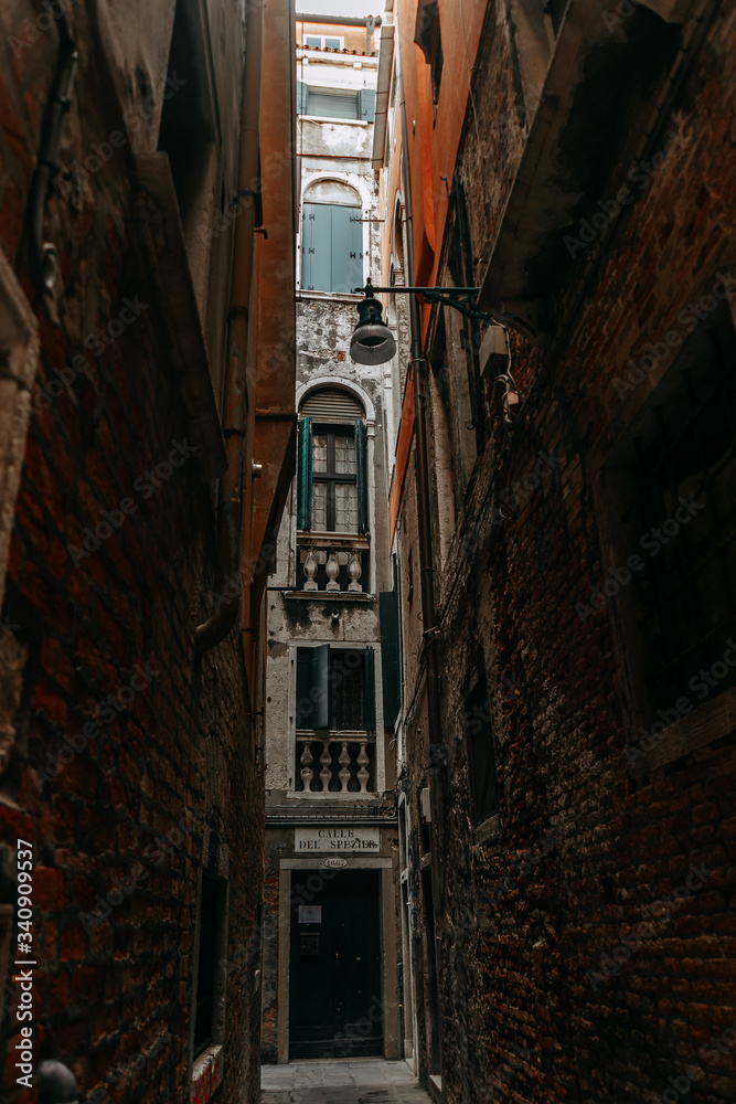 Narrow streets of Venice with tall houses made of wild stone and a single street lamp where the locals live | VENICE, ITALY - 16 SEPTEMBER 2018. 