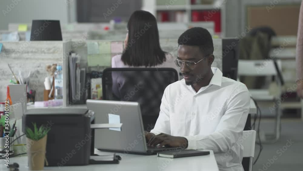 international office, african man manager working at the computer with documents and communicate with woman colleague in an open space. international office, african man manager working at the computer with documents and communicate with woman colleague in an open space.