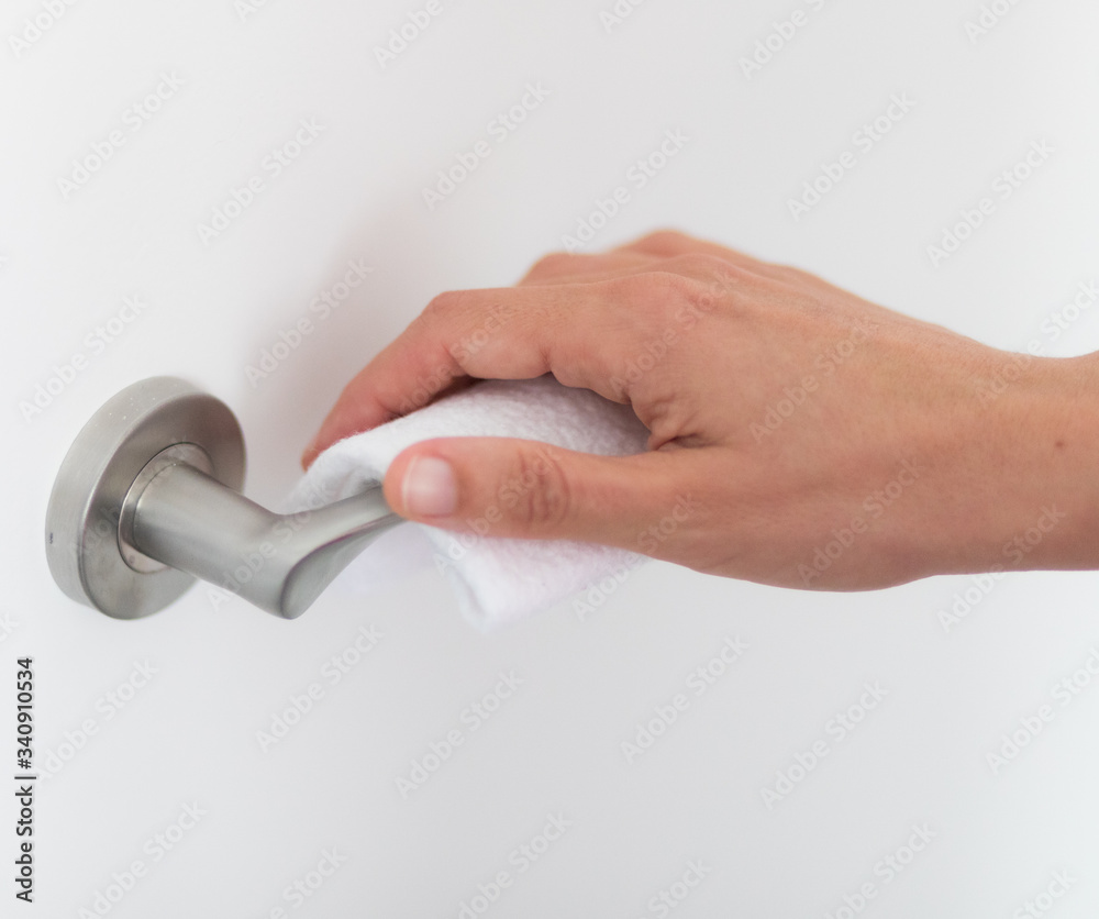 A hand opens a door with the help of a towel to avoid spreading viruses - obrazy, fototapety, plakaty 