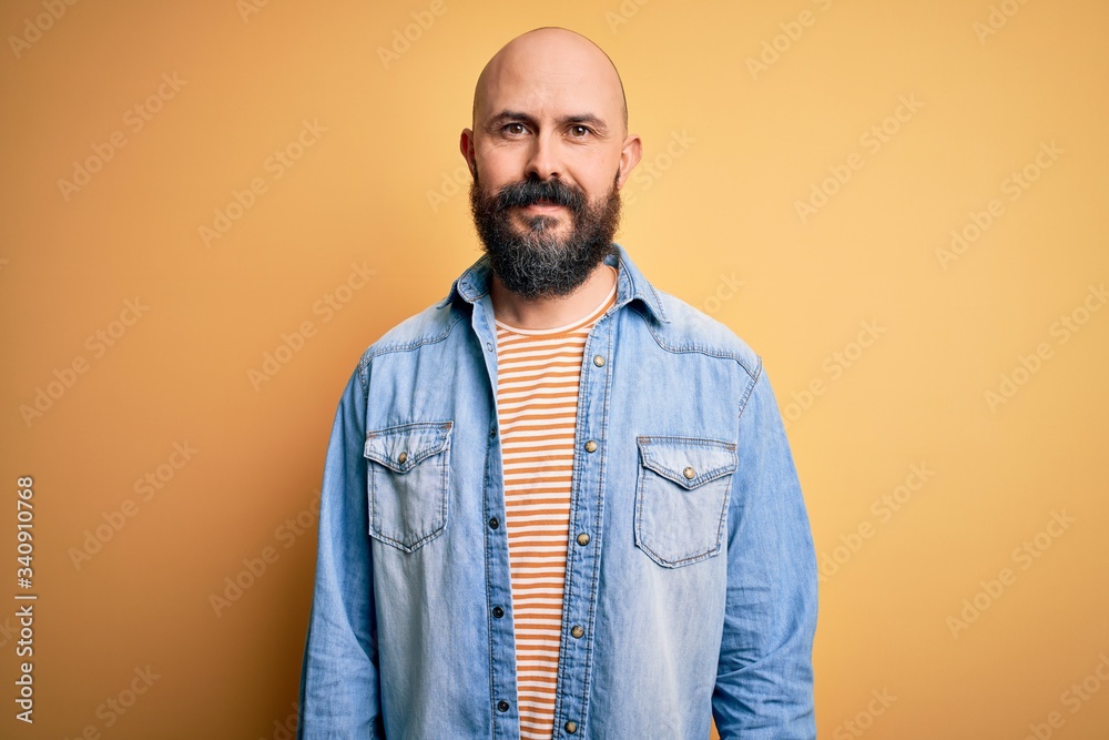 Handsome bald man with beard wearing casual denim jacket and striped t-shirt with a happy and cool smile on face. Lucky person. Handsome bald man with beard wearing casual denim jacket and striped t-shirt with a happy and cool smile on face. Lucky person.