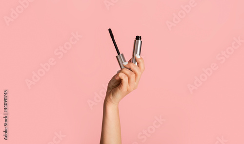 Beauty and makeup. Young girl holding mascara on pink background, close up photo