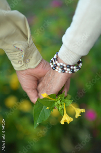 Couple holding hands with flowers сlose up 