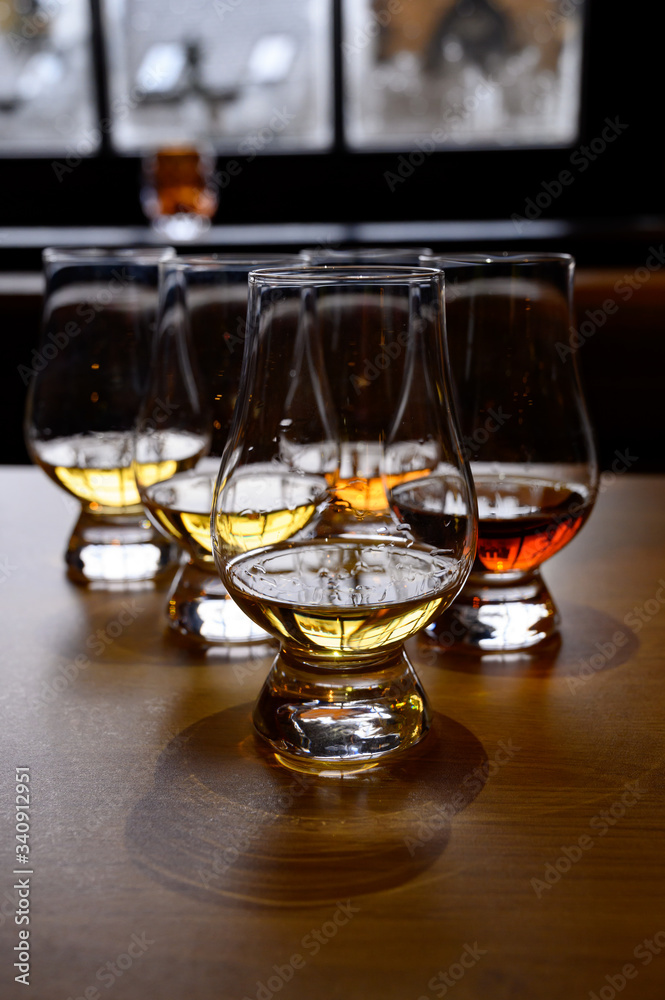 Obraz premium Flight of Scottish whisky, tasting glasses with variety of single malts or blended whiskey spirits on distillery tour in Scotland