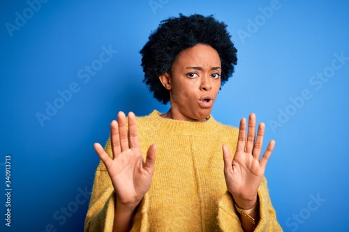 Photography Young beautiful African American afro woman with curly hair wearing yellow casual sweater Moving away hands palms showing refusal and denial with afraid and disgusting expression