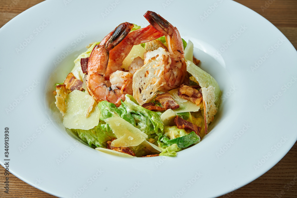 Appetizing Caesar with prawns, bacon, lettuce, parmesan and croutons in a white bowl. Seafood salad. Close up view Appetizing Caesar with prawns, bacon, lettuce, parmesan and croutons in a white bowl. Seafood salad. Close up view