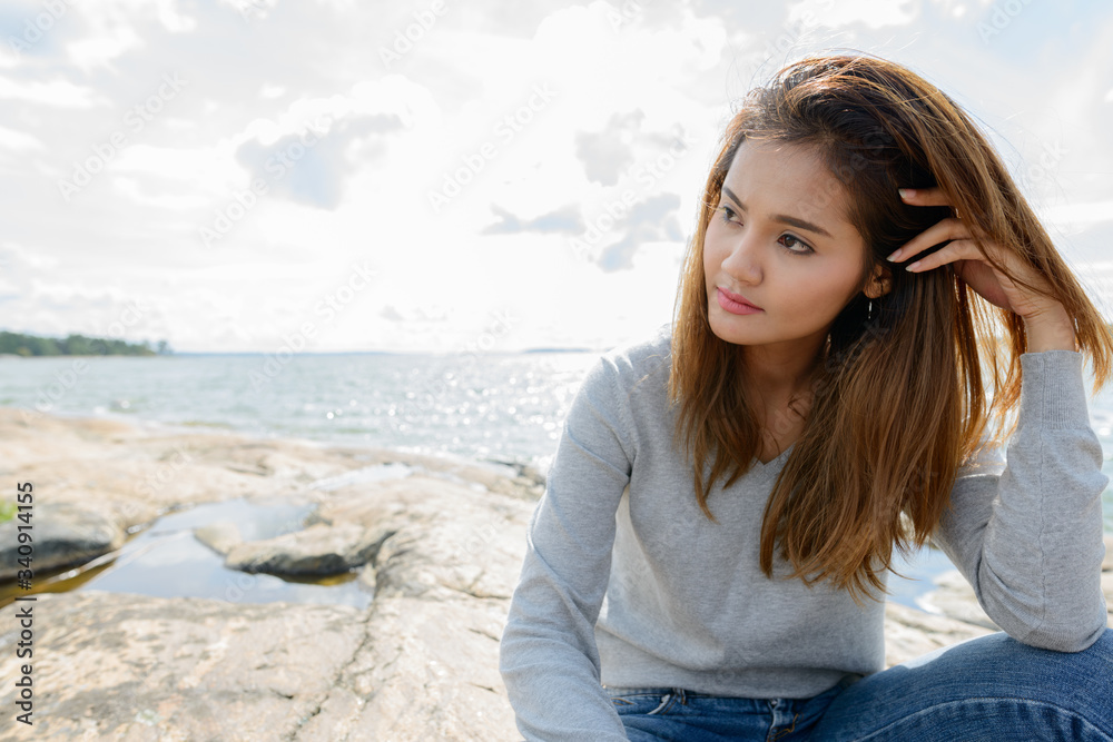 Young beautiful Asian woman against scenic view of the lake Young beautiful Asian woman against scenic view of the lake