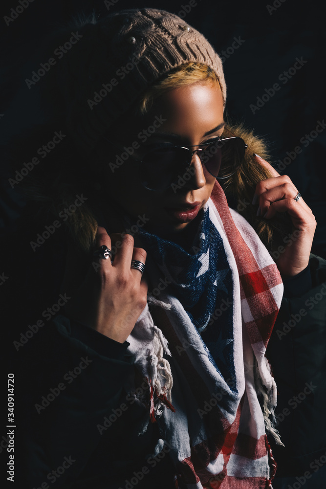 Girl portrait with modern short hairstyle, sunglasses, cap and scarf in studio.