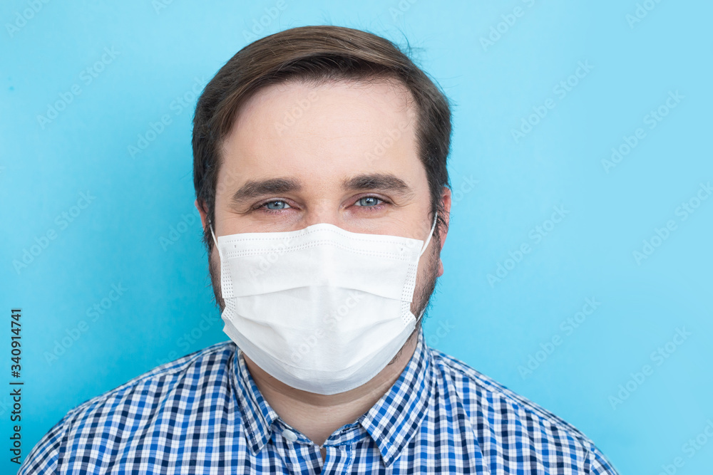Man wearing medical mask on blue background, copyspace, copyplace, space for text. Coronavirus, illness, infection, quarantine, medical mask Man wearing medical mask on blue background, copyspace, copyplace, space for text. Coronavirus, illness, infection, quarantine, medical mask