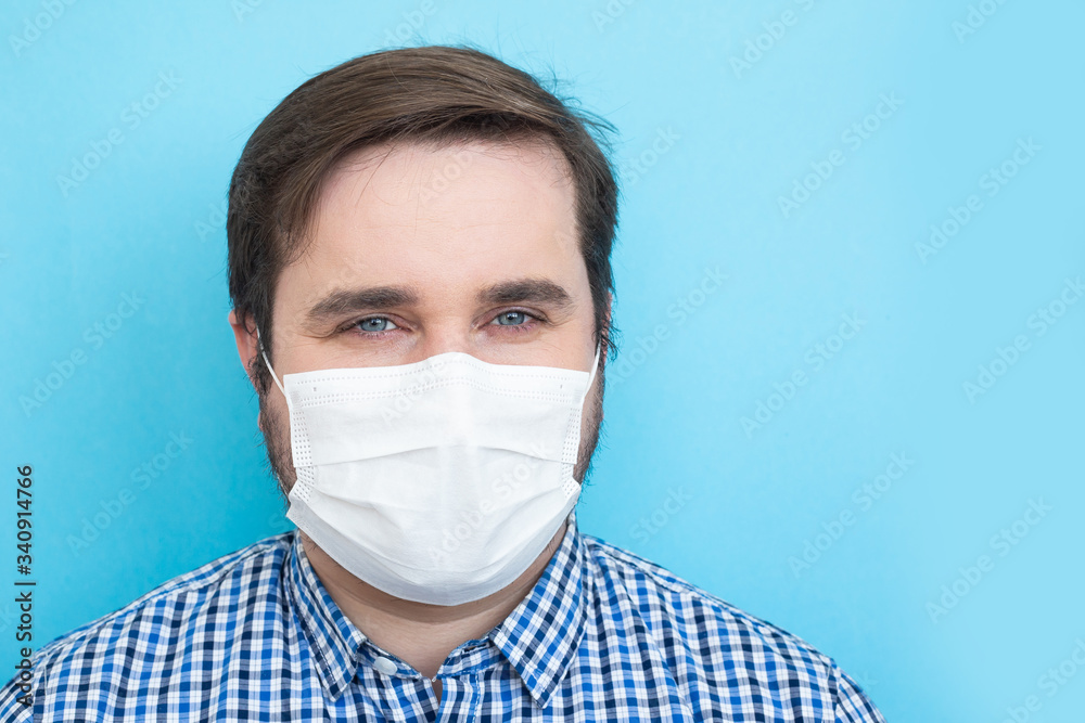 Man in medical mask on blue background, copyspace, copyplace, space for text. Coronavirus, illness, infection, quarantine, medical mask Man in medical mask on blue background, copyspace, copyplace, space for text. Coronavirus, illness, infection, quarantine, medical mask