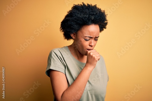 Young beautiful African American afro woman with curly hair wearing casual t-shirt feeling unwell and coughing as symptom for cold or bronchitis. Health care concept. © Krakenimages.com