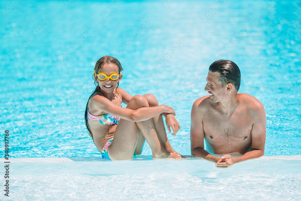 Family of mom and little daughter enjoying summer vacation in luxury swimming pool