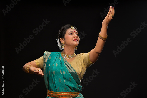 Beautiful kathak dancer performing gracefully over a dark background. 
 photo