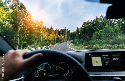 Obraz na płótnie Hands of car driver on steering wheel, fast driving car at spring day on a country road, having fun driving the empty highway on tour journey - POV, first person view shot w salonie