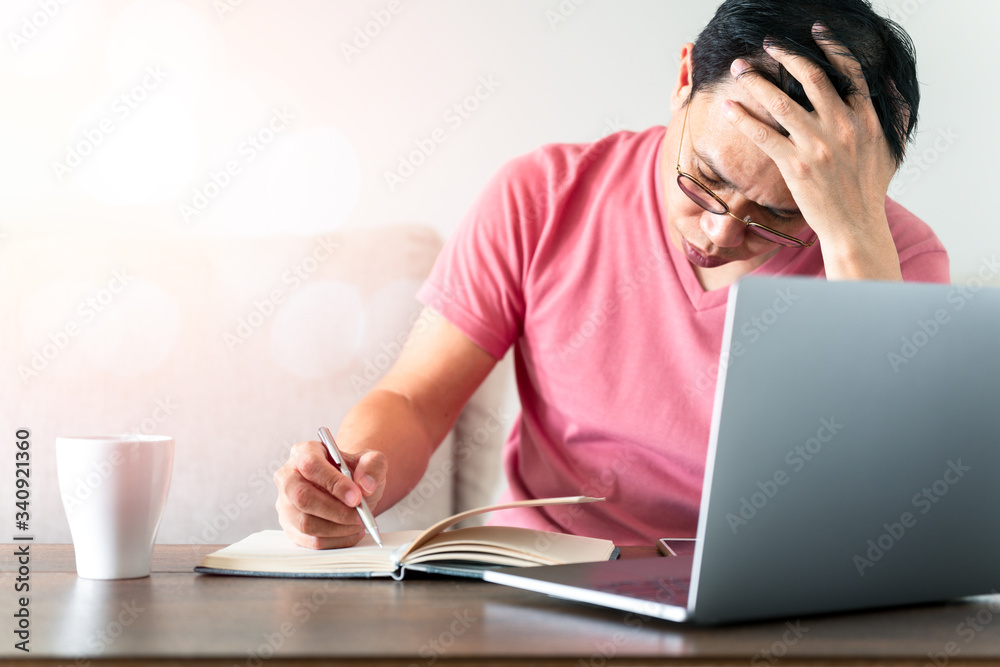 Asian man wear T-shirt, remote working, thinking and writing notebook on the wood table with technology equipment device. Asian man wear T-shirt, remote working, thinking and writing notebook on the wood table with technology equipment device.