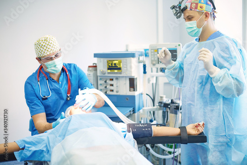 Several doctors surrounding patient on operation table during their work. Team surgeons at work in operating room