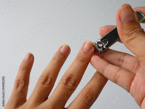 The left fingernail is cut by a nail clippers. The fingernails  harbor dirt and germs and can contribute to the spread of some infections nail, so that the grooming is a important self-care routine.