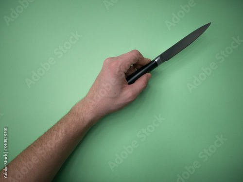 Hands hold professional kitchen knife isolated on green background. Top view.