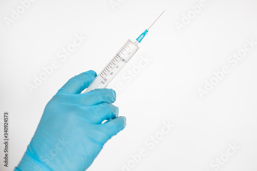Hand in glove holding syringe with vaccine for virus