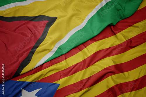 waving colorful flag of catalonia and national flag of guyana.
