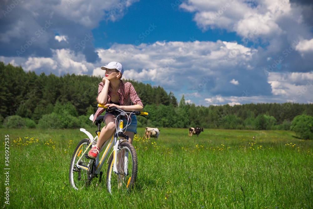 a young woman with a Bicycle in a summer meadow on a Sunny day a young woman with a Bicycle in a summer meadow on a Sunny day