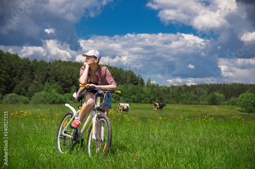 a young woman with a Bicycle in a summer meadow on a Sunny day