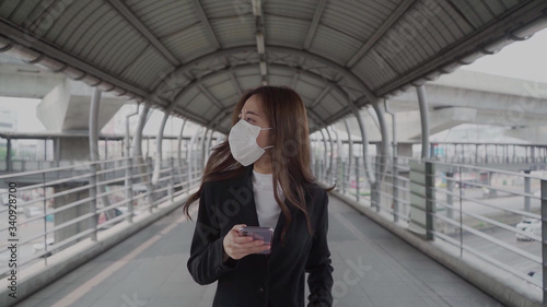 Wallpaper Mural Asian businesswoman wears black formulas and wears a mask Using a mobile phone and a smartphone while commuting to work During the Coronavirus epidemic
 Torontodigital.ca