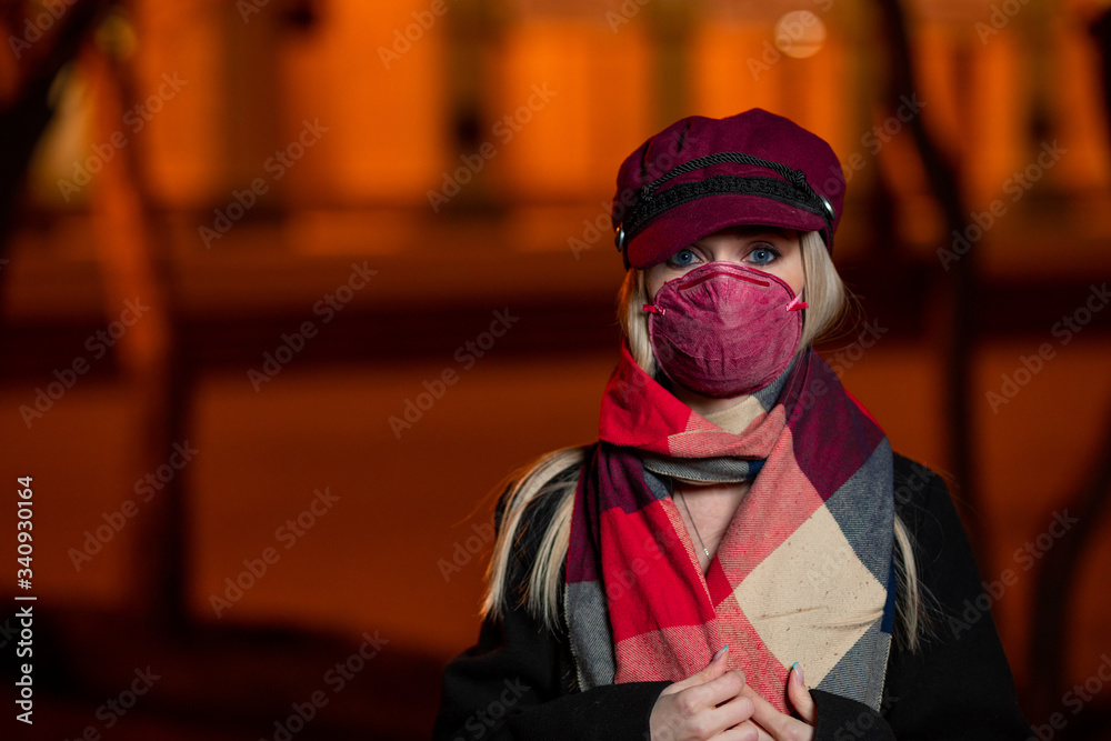 Obraz premium a girl in a black coat and in a red mask walks around the city at night
