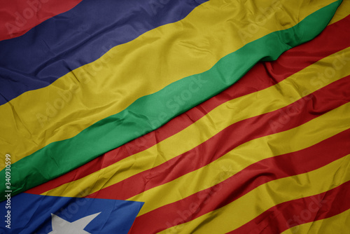 waving colorful flag of catalonia and national flag of mauritius.