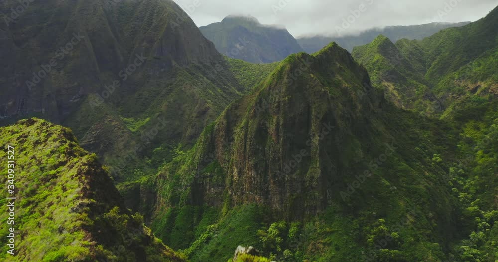 Cinematic aerial view flying over lush green mountain peaks in Hawaii