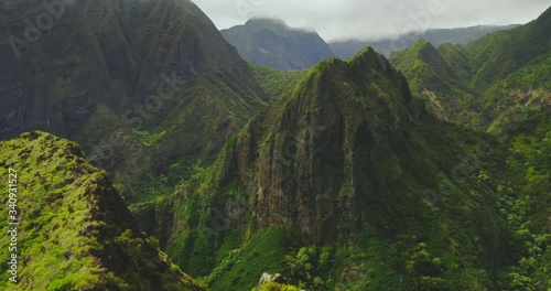 Cinematic aerial view flying over lush green mountain peaks in Hawaii