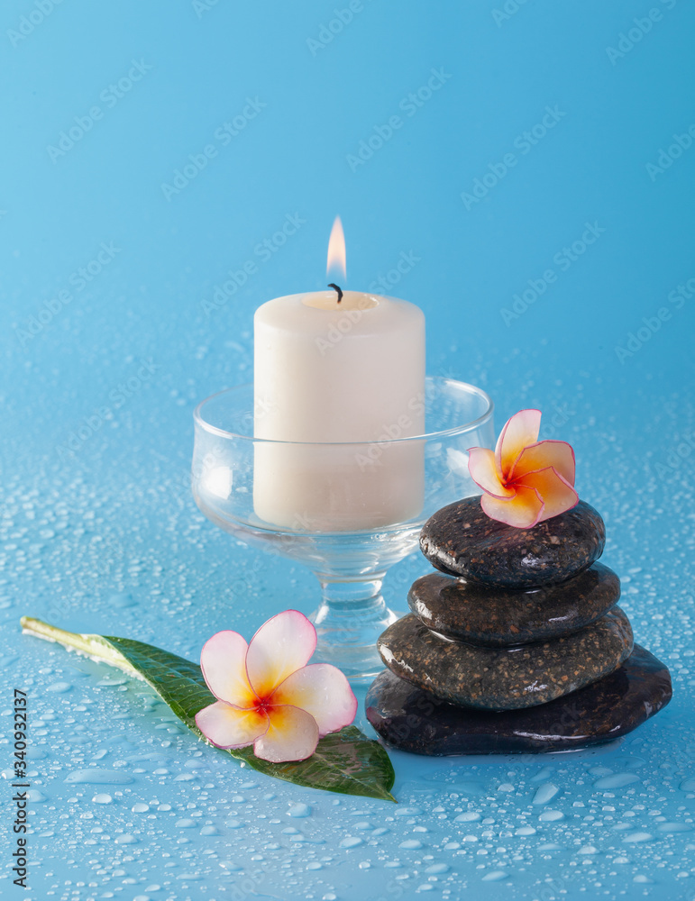 Spa stone pile with flowers and water drops on a blue background Spa stone pile with flowers and water drops on a blue background
