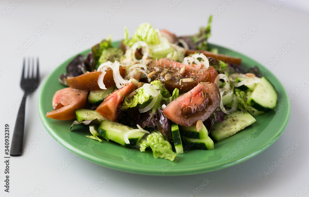 vegetable salad of greens, tomatoes and cucumbers on a green plate vegetable salad of greens, tomatoes and cucumbers on a green plate