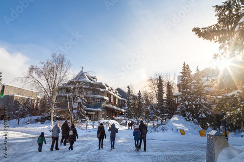People walking around in Whistler Village, Canada, which is populated with shops and resaurants. Faces and signs blurred out.