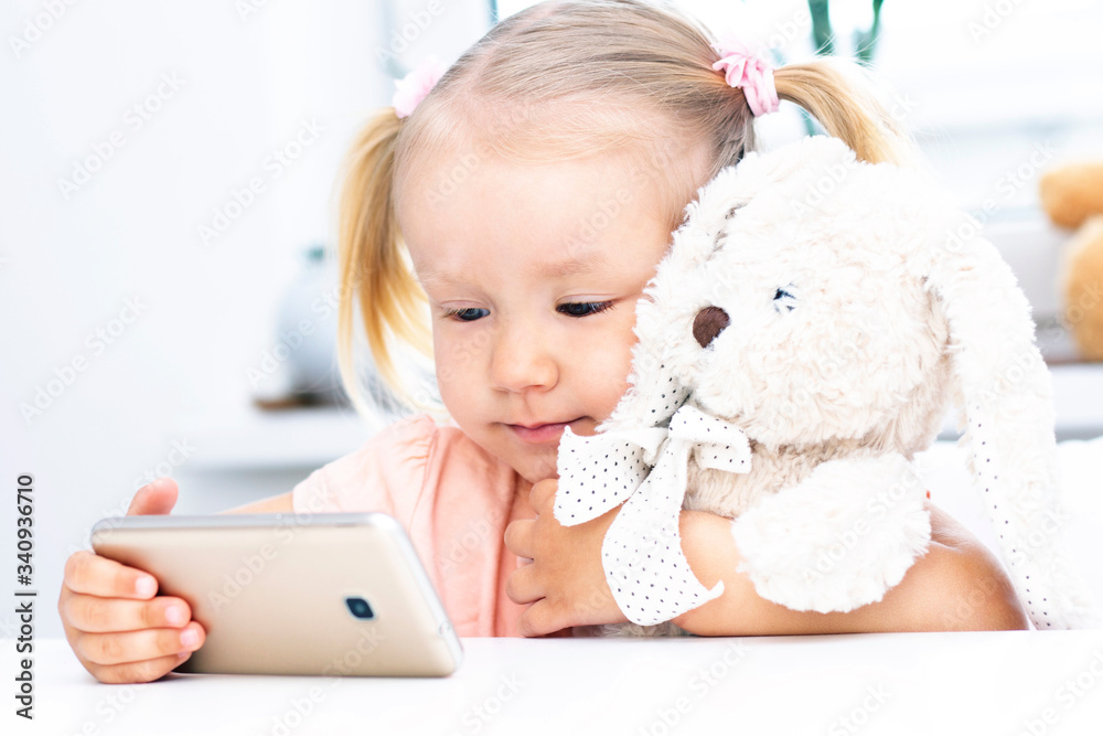 Girl with a toy bunny using a mobile phone, a smartphone for video calls, talking with relatives, a girl sitting at home, online computer webcam, making a video call. Girl with a toy bunny using a mobile phone, a smartphone for video calls, talking with relatives, a girl sitting at home, online computer webcam, making a video call.