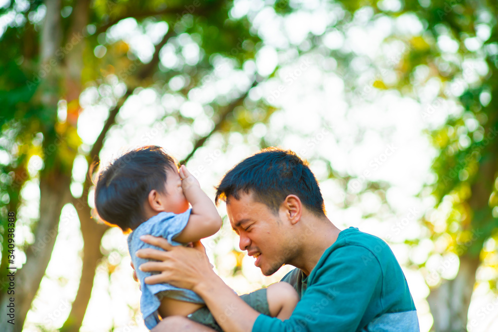Portrait of happy father holding baby son hand carry up in city park sunset light. Portrait of happy father holding baby son hand carry up in city park sunset light.