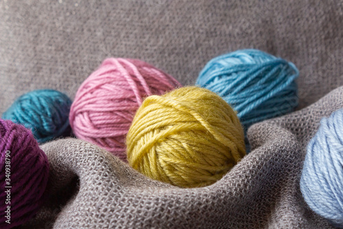 Knitting hobby. Multi-colored tubes of wool on gray plaid. Cozy hugge hobby. Close up.