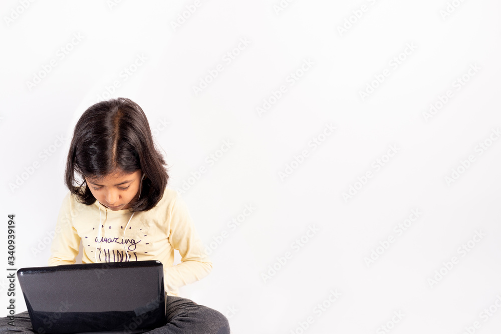 Cute little girl is using her notebook and headphones