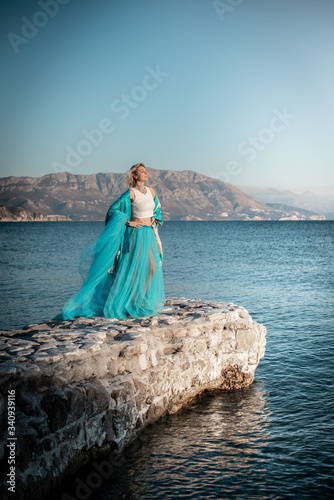Young woman on the sea in blue dress