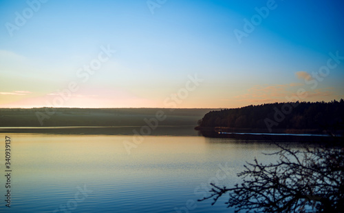 Peaceful rural landscape. Beautiful river with blue sky above at sunrise.