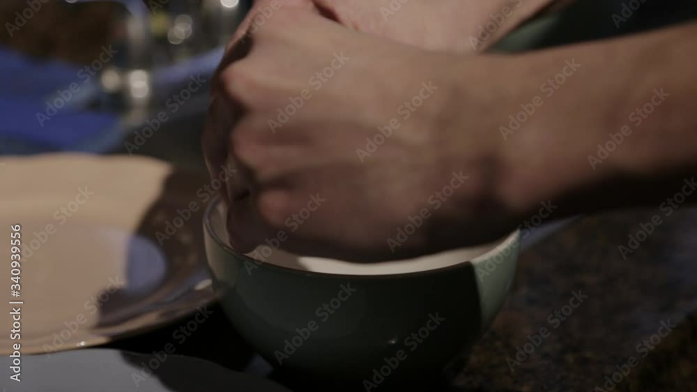 A Pair Of Hands Cracking Egg Into A Ceramic Bowl Beside The Kitchen Sink.- closeup shot A Pair Of Hands Cracking Egg Into A Ceramic Bowl Beside The Kitchen Sink.- closeup shot