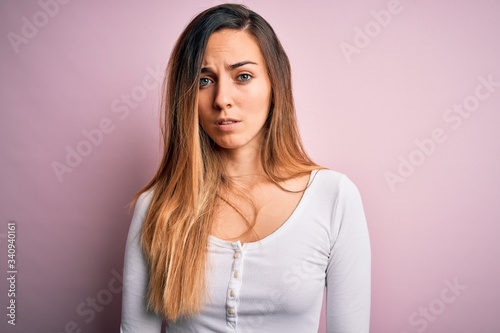Young beautiful blonde woman with blue eyes wearing white t-shirt over pink background skeptic and nervous, frowning upset because of problem. Negative person. © Krakenimages.com
